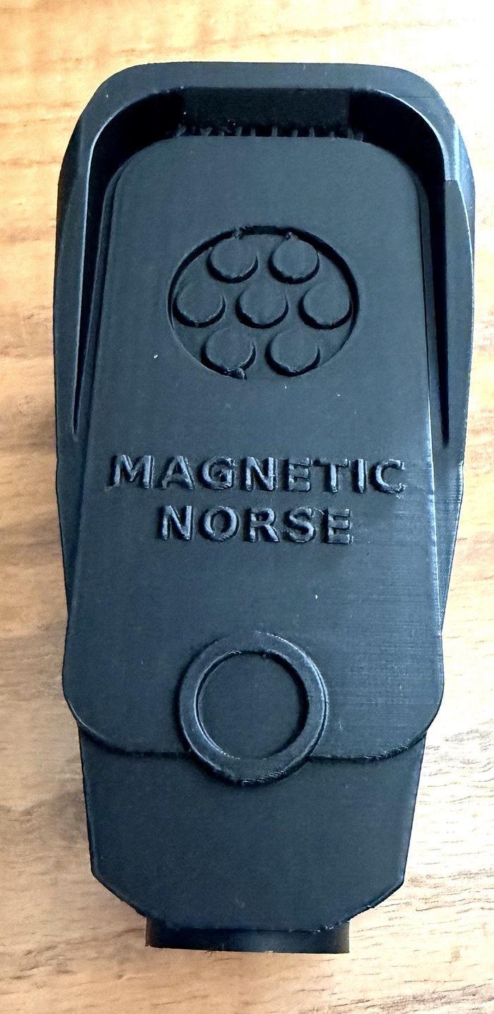 The printed Dragnet Node on a table, MAGNETIC NORSE raised across the face above the lens.